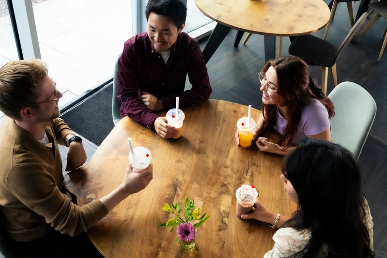 Een groep vrienden aan tafel, van boven gefotografeerd